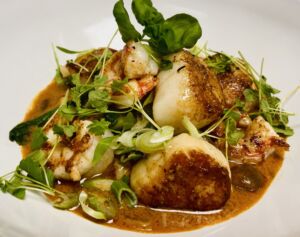 Seared scallops on a plate garnished with greens.